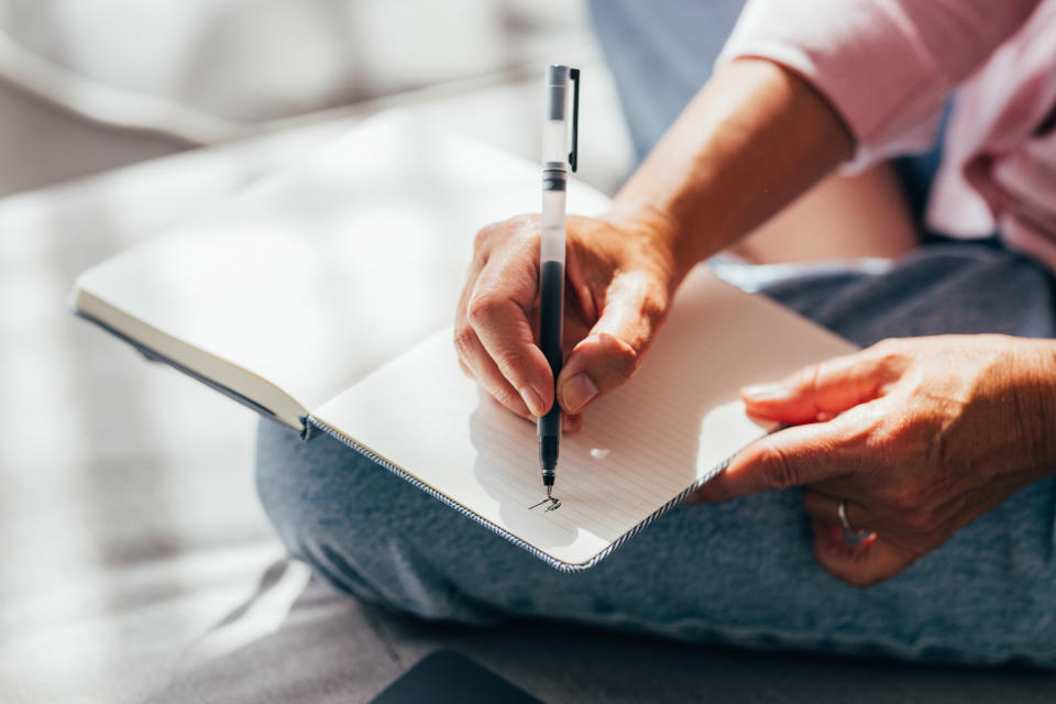 A close-up photo capturing a person's hands as they write in a ruled notebook, possibly for planning, journaling, or note-taking.