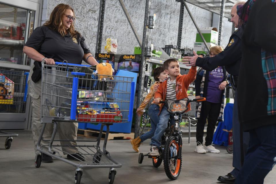 Bradlee Malone, 5, high-fives a police officer from his new bike during the Columbia County Sheriff's Office Day with a Deputy at Walmart on Thursday, Dec. 21, 2023.