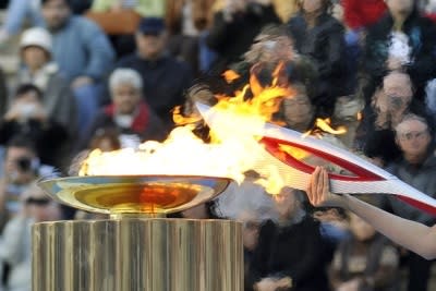 A woman lights the Olympic Flame during the Olympic Torch Handover Ceremony, on October 05, 2013 in Athens, Greece.