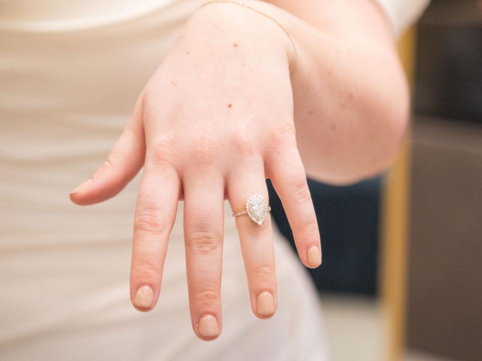 A woman holds her hand out with a ring on her finger.