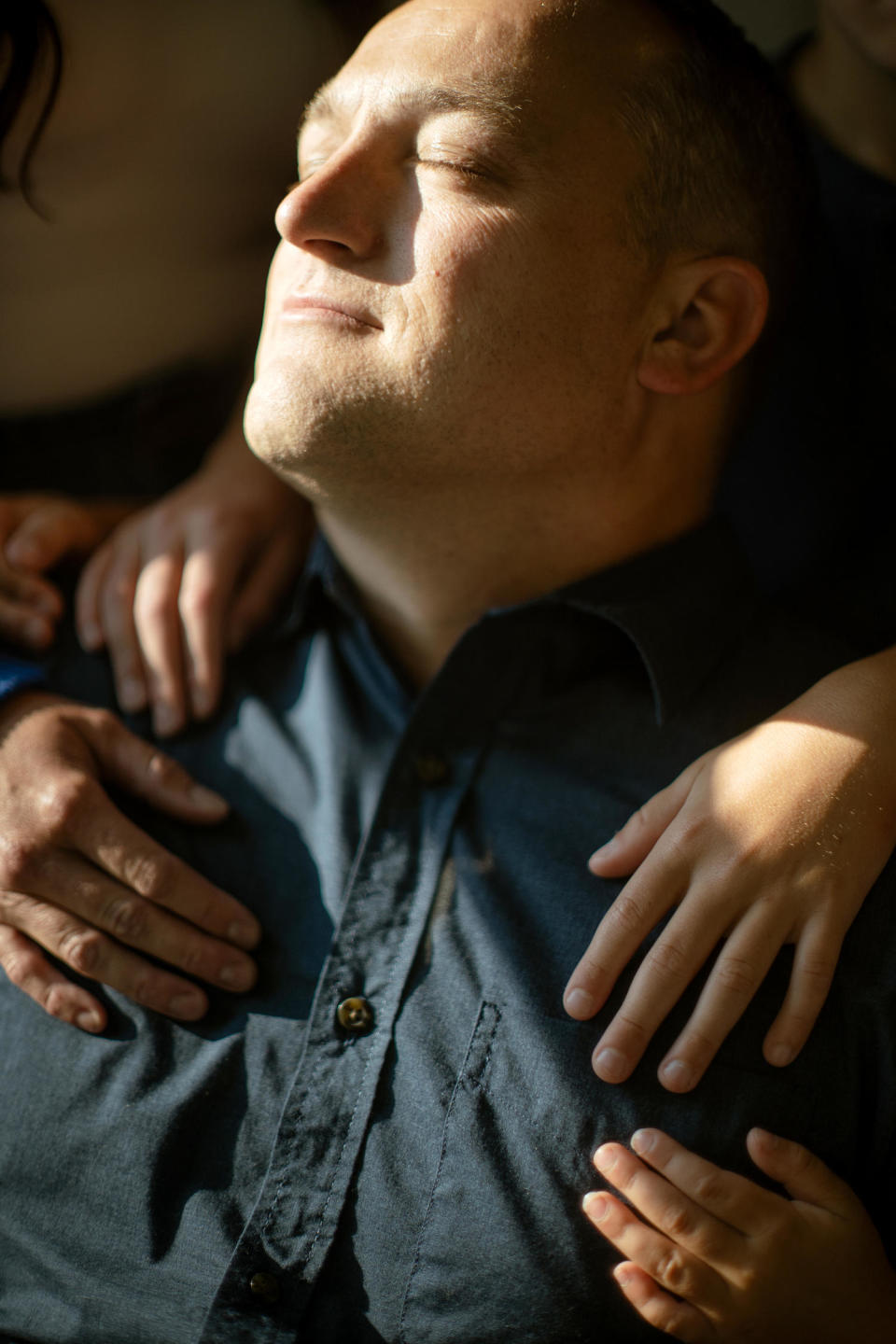 David Bennett Jr. closes his eyes while his family hugs him. (Rosem Morton for NBC News)