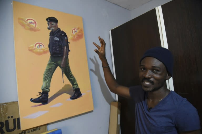 Artist Julius Agbaje shows a painting of a police officer with dog's head, entitled 'Mad Dog'