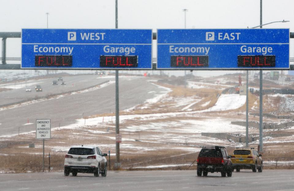 Vehicles drive toward Denver International Airport in the snow on Friday, Nov. 24, and beneath signs warning that all of the airport's close-in parking options are full.