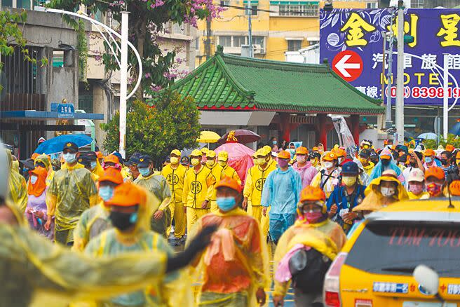 「粉紅超跑」著雨衣繼續趕路，不過再大的雨都澆不熄香燈腳的熱情，上萬信眾與媽祖一同著雨衣繼續前行。（吳建輝攝）