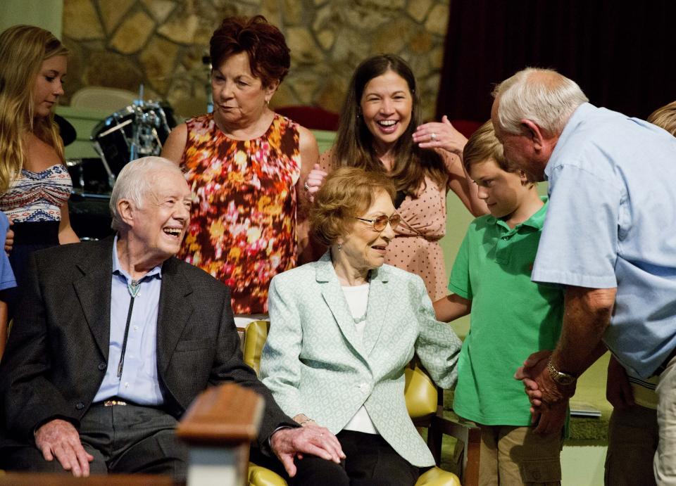 Former President Jimmy Carter, left, sits with his wife Rosalynn as they pose for photos with Bill Bush, of Adel, Ga., from right, his grandson Carson Shirley, 9, daughter Lara Norris, and wife Pat Bush after Carter taught Sunday School class at Maranatha Baptist Church in his hometown Sunday, Aug. 23, 2015, in Plains, Ga. (AP Photo/David Goldman)