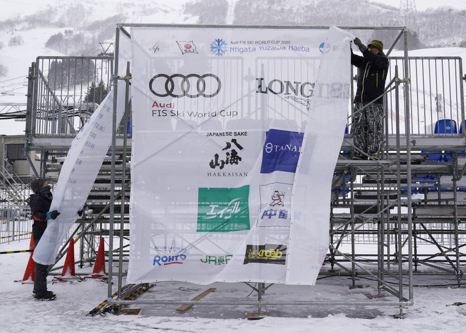 Event staff remove signage from the venue after it was announced that the men's slalom race has been cancelled due to weather conditions during the 2020 Audi FIS Alpine Ski World Cup at Naeba Ski Resort in Yuzawa, Niigata prefecture, northern Japan, Sunday, Feb. 23, 2020. (AP Photo/Christopher Jue)