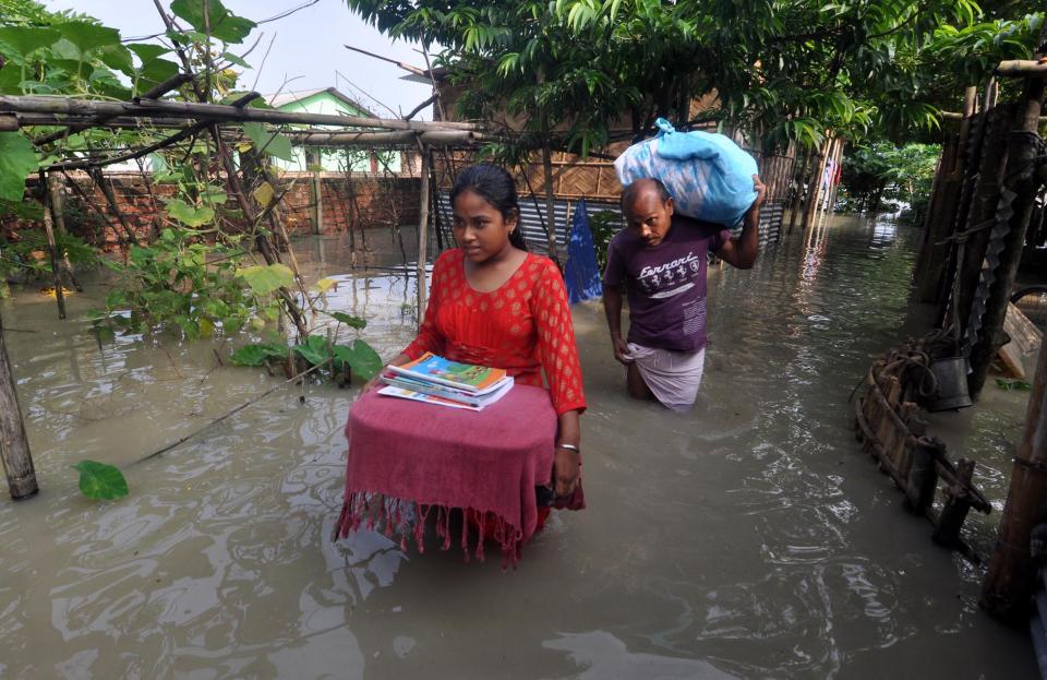 Villagers move to a safer place from the flooded area of Hatisela in Kamrup district of Assam. (Photo credit should read Anuwar Ali Hazarika/Barcroft Media via Getty Images)