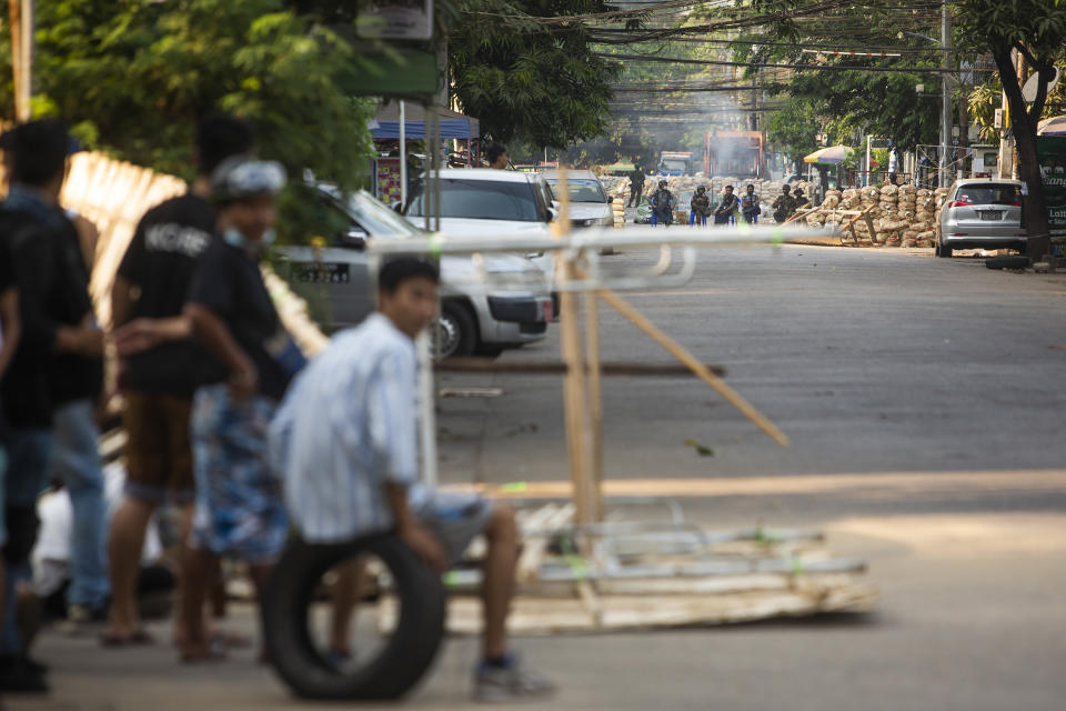 Locals watch police and military occupying a road block barricade in Yangon, Myanmar, Friday, March 19, 2021. The authorities in Myanmar have arrested a spokesman for ousted leader Aung San Suu Kyi's political party as efforts to restrict information about protests against last month's military takeover are tightened. (AP Photos)