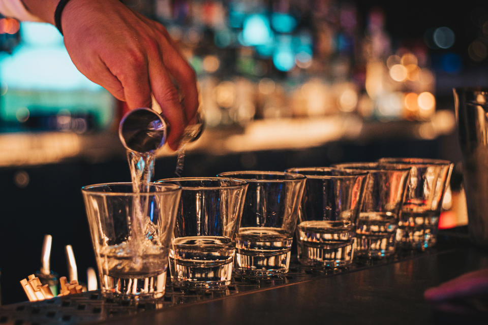 Bartender pouring shots all in a row.