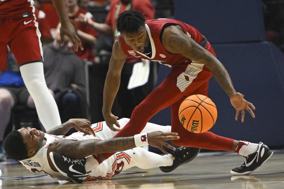 Auburn guard K.D. Johnson passes the ball from the floor as as Arkansas guard Davonte Davis defends during the first half of an NCAA college basketball game in the second round of the Southeastern Conference men's tournament Thursday, March 9, 2023, in Nashville, Tenn. (AP Photo/John Amis)