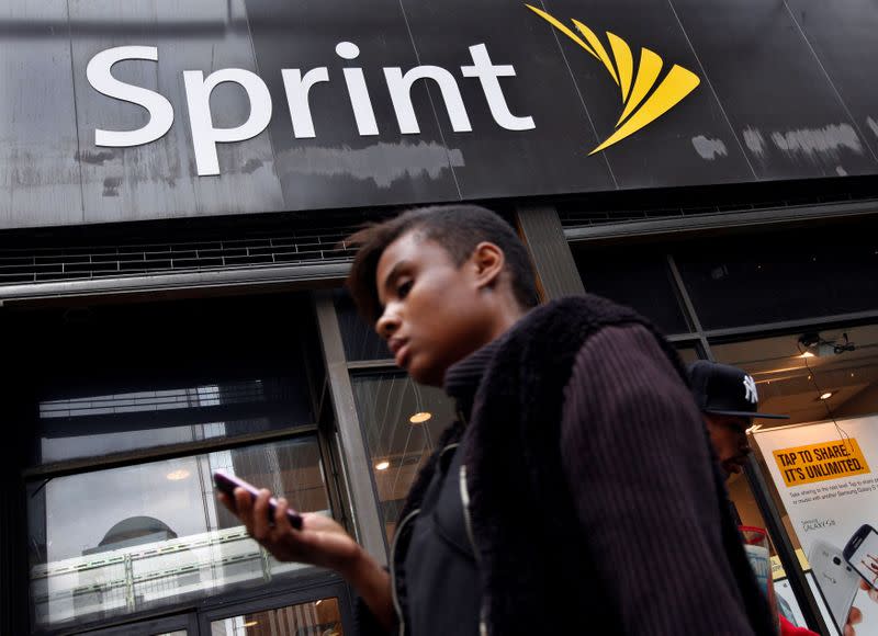 FILE PHOTO: A woman uses her phone as she walks past a Sprint store in New York's financial district