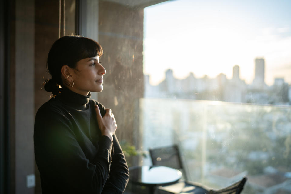 A woman looks out her window at the city skyline