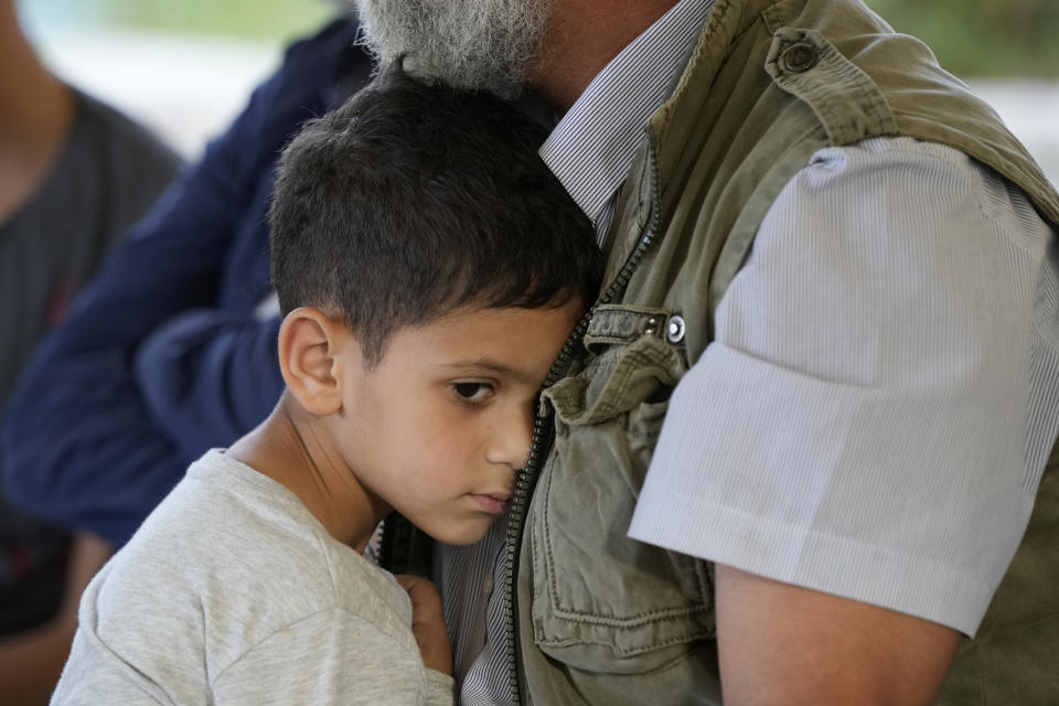 A boy hugs his father as Dandashi family receive condolences, in Tripoli, Lebanon, Wednesday, April 27, 2022. A week ago, a boat carrying around 60 men, women and children on board, trying to escape their country and reach Europe sank in the Mediterranean after colliding with a Navy ship. 47 were rescued, seven bodies were found, and the rest remain missing. (AP Photo/Hassan Ammar)