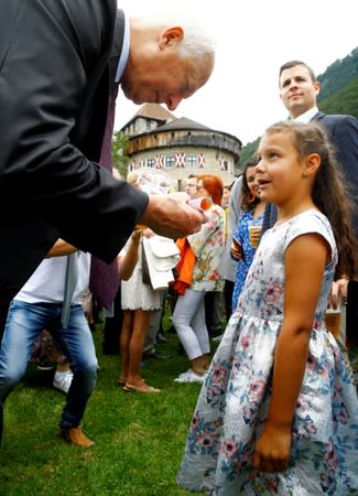 Nayla presents a rolled drawing to Prince Hans-Adam II of Liechtenstein during a party in the gardens of Schloss Vaduz castle in Vaduz August