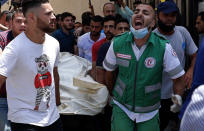 Medics and youths chant while carrying the covered body of a man, who was killed in Israeli airstrikes that hit his apartment building, in Gaza City, Tuesday, May 11, 2021. Since Monday, Gaza militants have fired hundreds of rockets toward Israel. Israel has fired back, hitting targets inside Gaza that included a high-rise building in the middle of Gaza City. (AP Photo/Adel Hana)