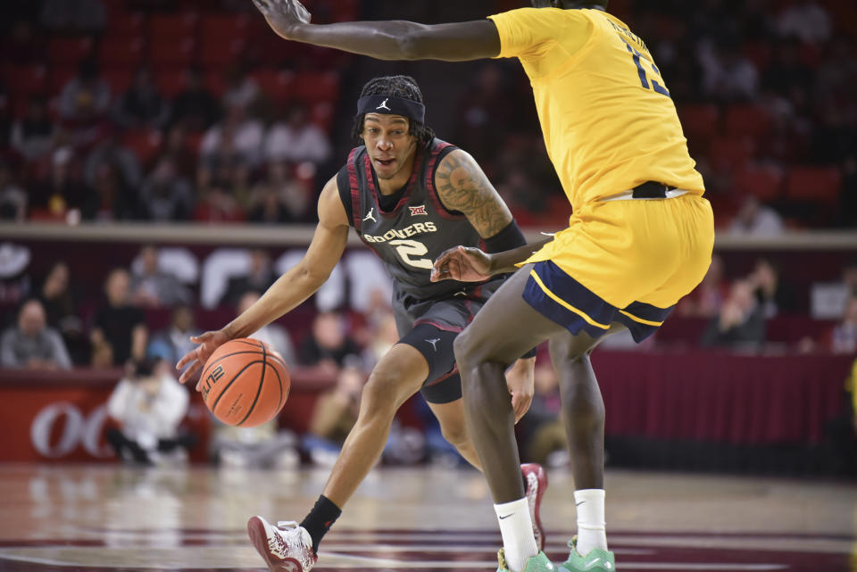 Oklahoma guard Javian McCollum, left, pushes past West Virginia forward Akok Akok during the first half of an NCAA college basketball game Wednesday, Jan. 17, 2024, in Norman, Okla. (AP Photo/Kyle Phillips)