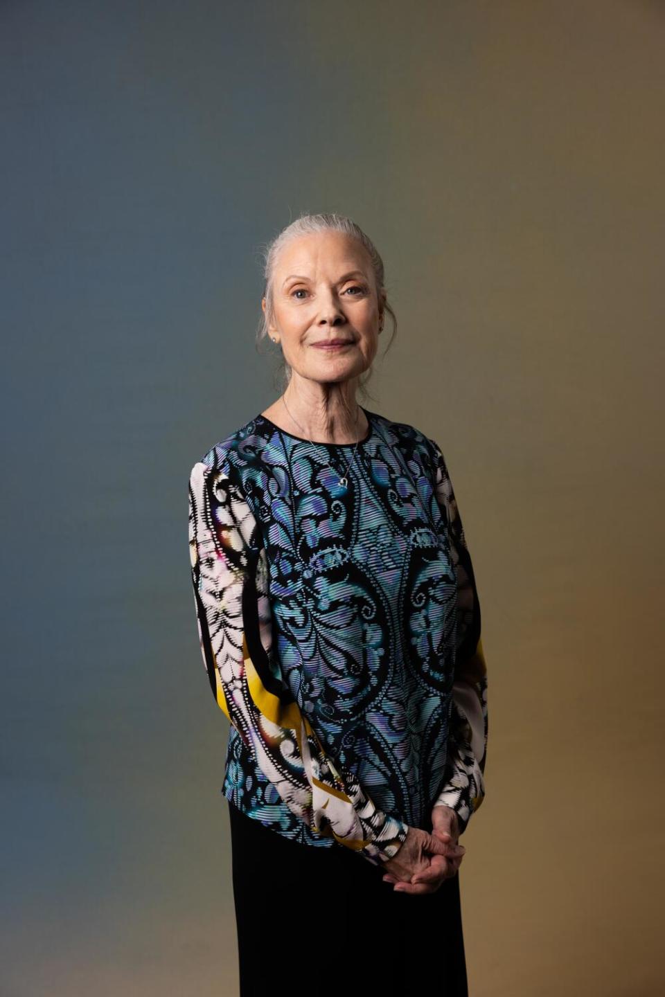 Karen Kain in a patterned blouse stands and smiles.