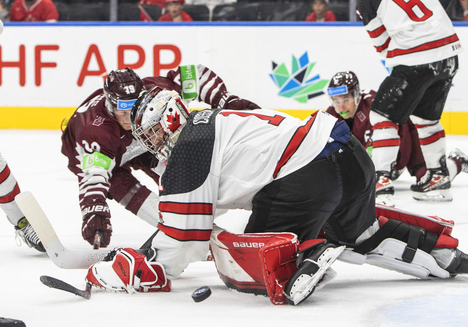 Canada goalie Sebastian Cossa (1) makes the save on Latvia's Darels Dukurs (19) during the third period of an IIHF junior world hockey championships game Wednesday, Aug. 10, 2022, in Edmonton, Alberta. (Jason Franson/The Canadian Press)