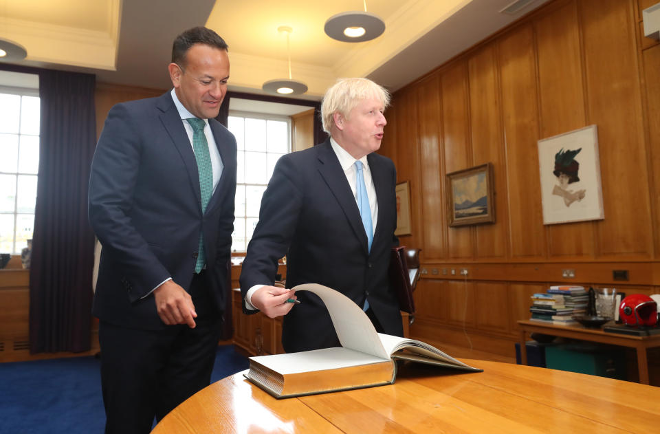 Prime Minister Boris Johnson signing the visitors' book as Taoiseach Leo Varadkar welcomes him to the Government Buildings in Dublin.