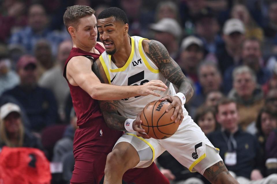 Utah Jazz forward John Collins drives on Cleveland Cavaliers guard Sam Merrill during the first half of an NBA basketball game Wednesday, Dec. 20, 2023, in Cleveland. (AP Photo/David Dermer)