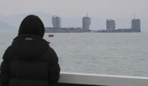 A relative of missing passengers of the sunken Sewol ferry watches workers lifting the boat in waters off Jindo, South Korea, Thursday, March 23, 2017. South Korean workers on Thursday slowly pulled up the 6,800-ton ferry from the water, nearly three years after it capsized and sank into the violent seas off South Korea's southwestern coast, an emotional moment for a country that continues to search for closure to one of its deadliest disasters ever. (Lee Jin-wook/Yonhap via AP)