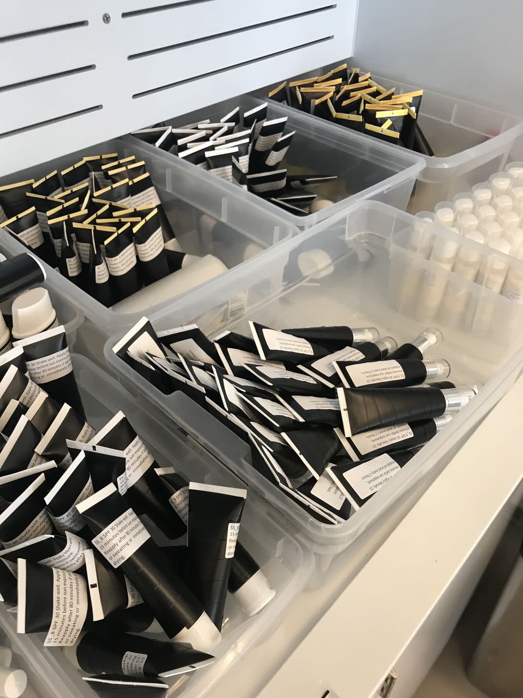 a collection of sunscreens with labels blinded in separate bins in the gh beauty lab