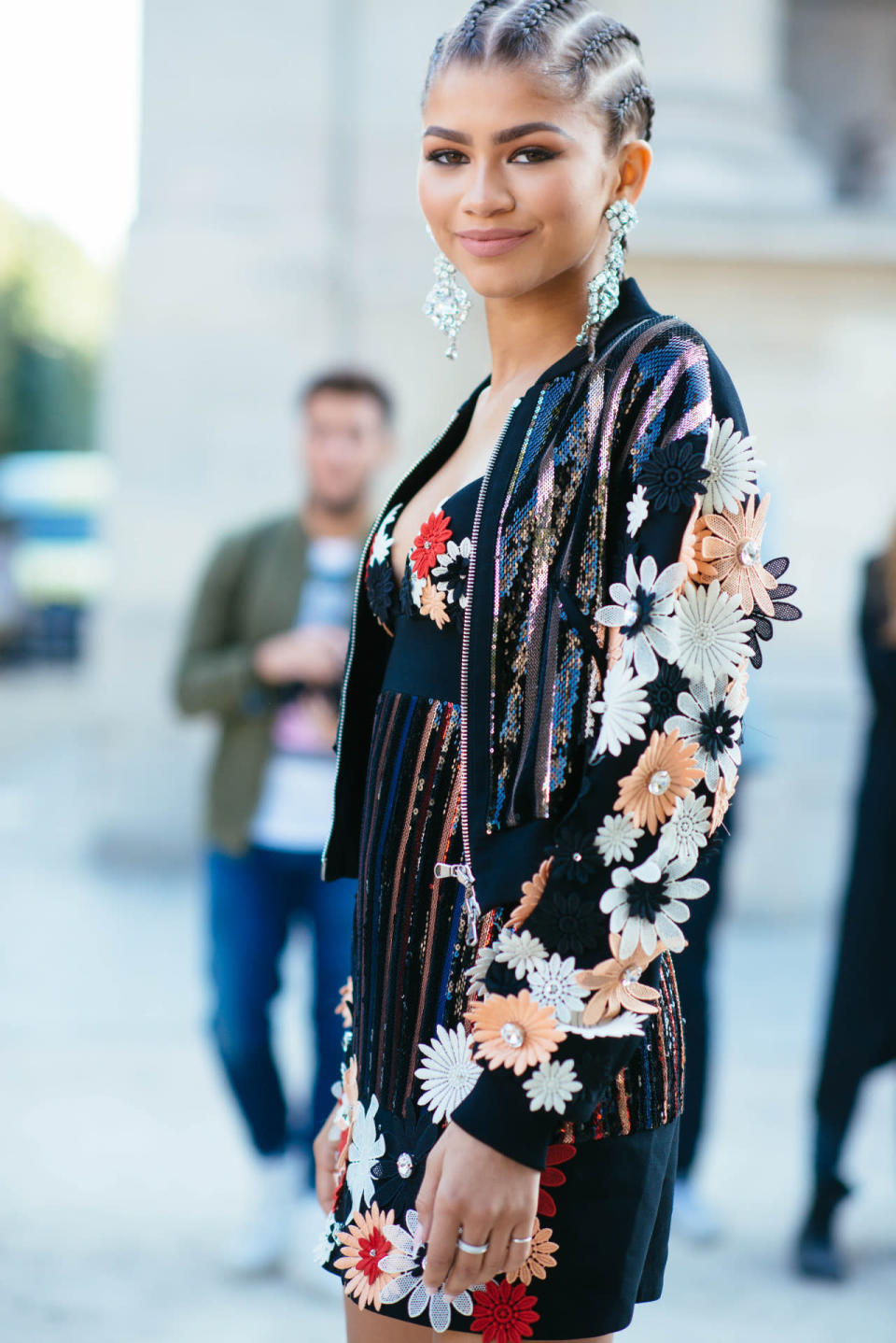 <p>Attending Emanuel Ungaro’s Spring 2016 fashion show, Zendaya paired a black dress covered in sequins and red, peach, pink, and white flowers blooming off it. She paired the mini with a matching bomber jacket made of the same elements. When she shared a pic of herself in this outfit, she captioned it cornrows and designer clothes. On her changing hairstyles, the <i>K.C. Undercover</i> star <a href="https://instagram.com/p/8aeV2rpmBT/?taken-by=zendaya" rel="nofollow noopener" target="_blank" data-ylk="slk:wrote on Twitter;elm:context_link;itc:0;sec:content-canvas" class="link ">wrote on Twitter</a>, “A guy came up to me and was like, ‘One show you have short hair, now you have braids, how?’ I turned over my shoulder and said…magic.” </p><p><i>Photo: BFA</i></p>