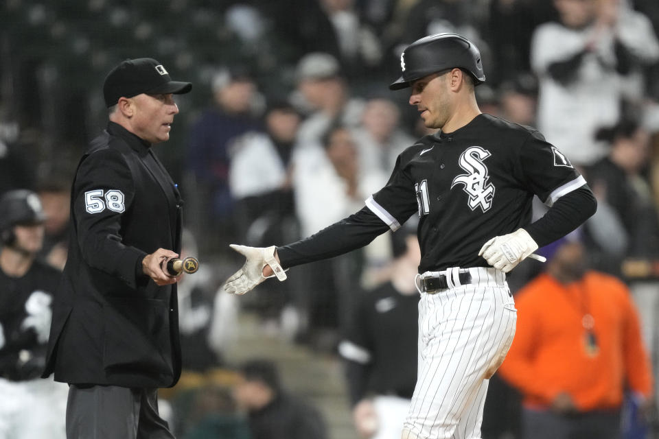 Home plate umpire Dan Iassogna hands Chicago White Sox's Adam Haseley the bat of Tim Anderson, after Haseley scored on Anderson's single against the Cleveland Guardians during the sixth inning of a baseball game Wednesday, May 17, 2023, in Chicago. (AP Photo/Charles Rex Arbogast)