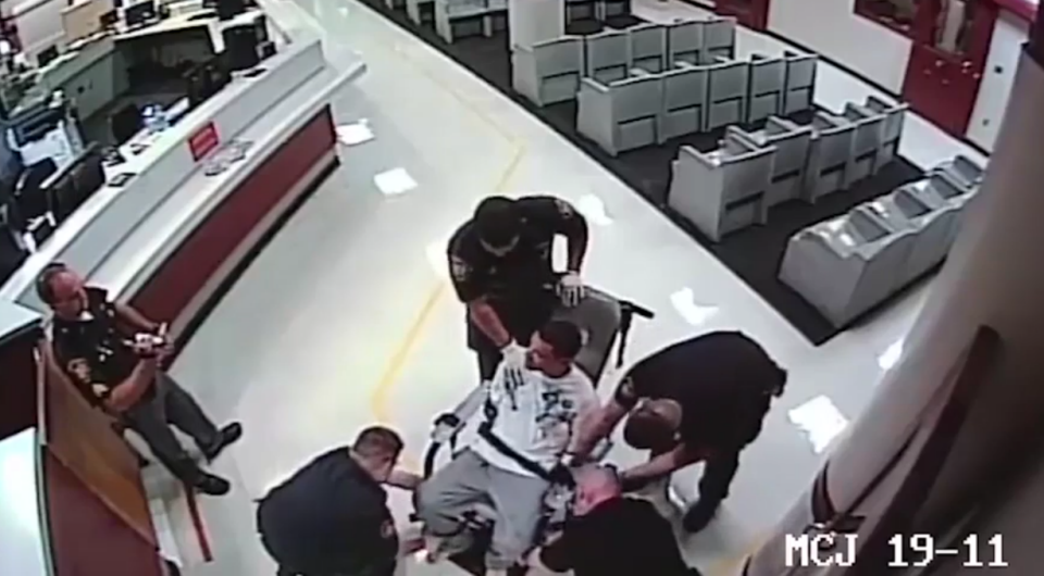 Officers strap him into the restraint chair. Photo: Liveleak