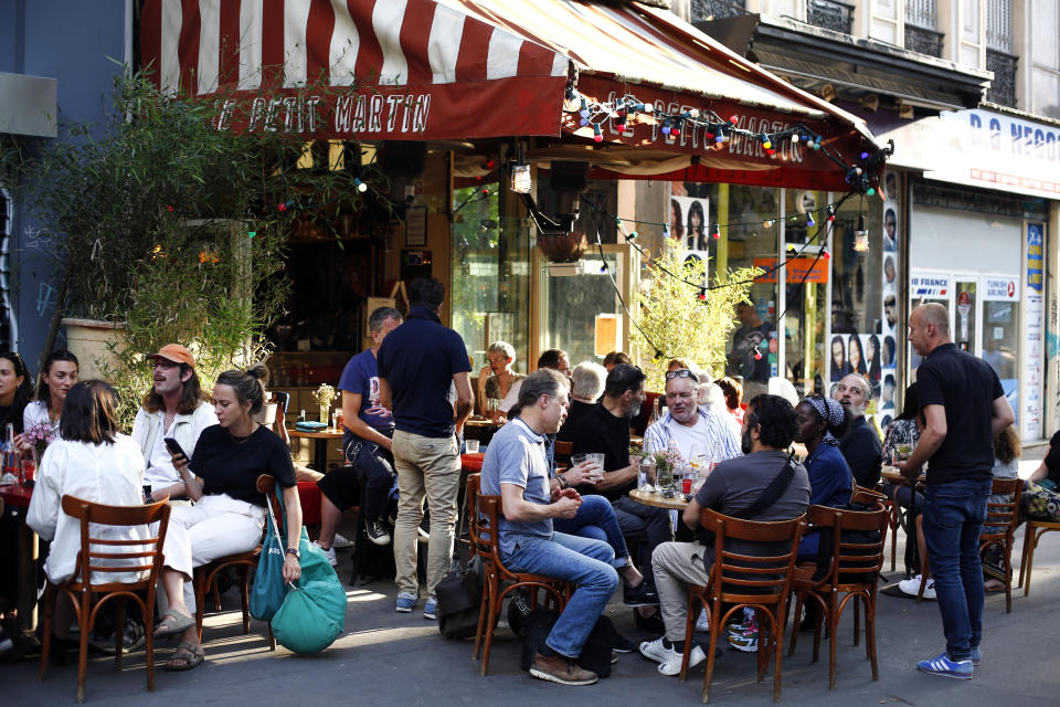 People sit on the terrace of a cafe in Paris, Tuesday, June 2, 2020. Paris City Hall authorized the reopening of outside seating areas but indoor tables remain closed to customers until at least June 22. (AP Photo/Thibault Camus)