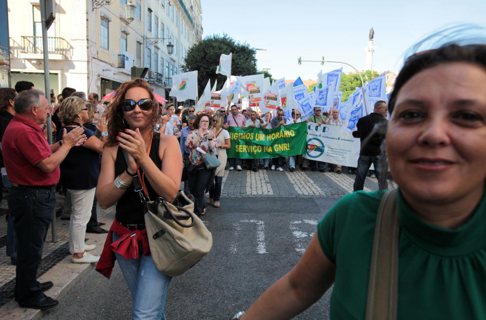 People react and applaud as members of the National Republican Guard and police professionals associations, in the background, join a workers unions' demonstration in Lisbon, Saturday, Sept. 29 2012. Thousands of Portuguese enduring deep economic pain from austerity cuts took to the streets Saturday in protest. (AP Photo/Armando Franca)