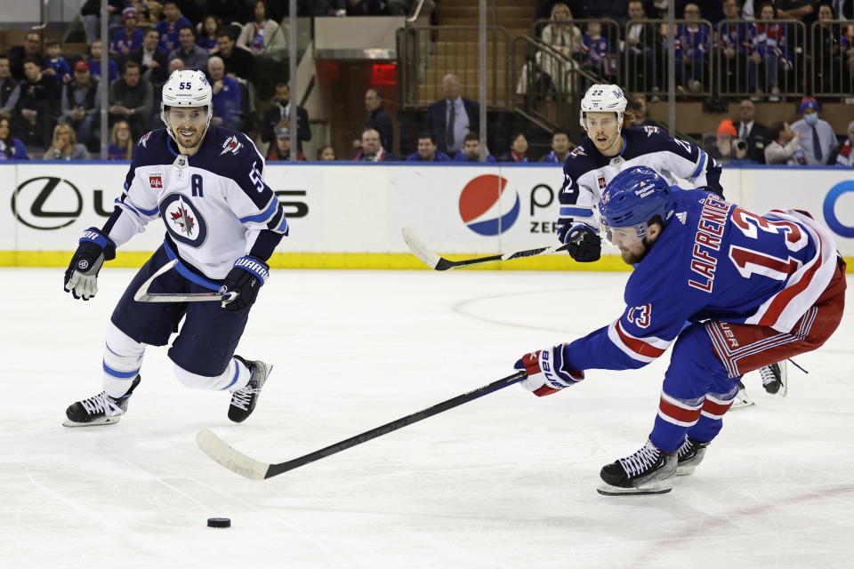 New York Rangers left wing Alexis Lafreniere (13) knocks the puck away from Winnipeg Jets center Mark Scheifele (55) in the first period of an NHL hockey game Monday, Feb. 20, 2023, in New York. (AP Photo/Adam Hunger)