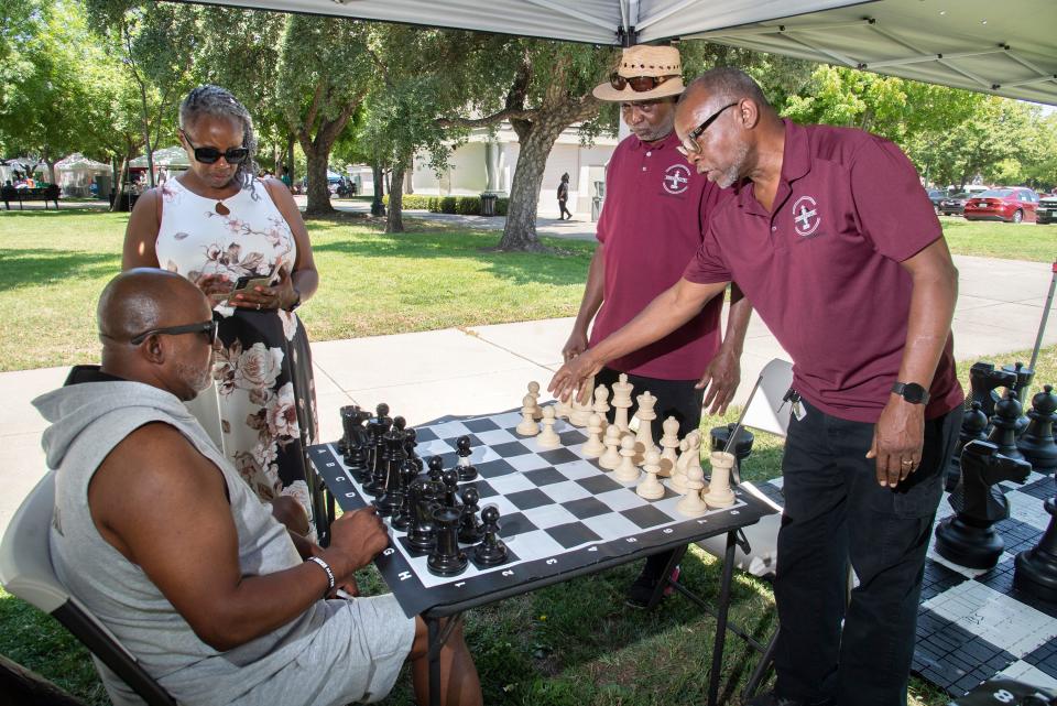 Norman Repass, 3rd from left, and Lenard Seawood, right, yeah James Robinson, left, and his wife Linda Robinson how to play chess at the Make Every Move County nonprofit mentorship's booth at the 2023 Juneteenth event at the Weber Point Events Center in downtown Stockton on June 17, 2023.