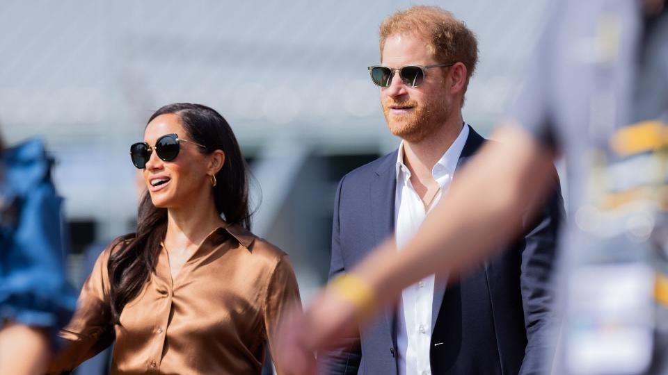 Prince Harry and Meghan Markle walking and holding hands whilst wearing sunglasses