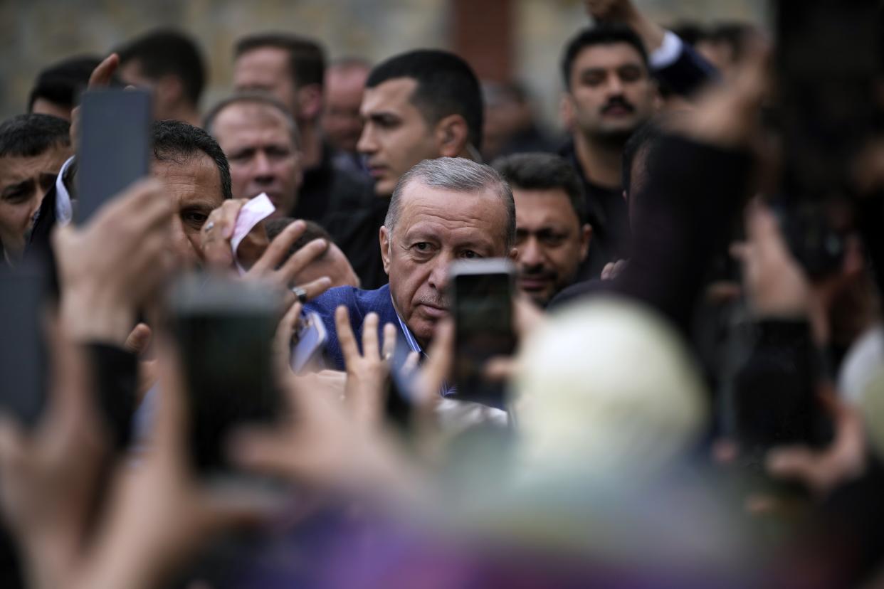 Turkish President and leader of the People Alliance party, presidential candidate Recep Tayyip Erdogan, gives money to a child after he casted his ballot at a polling station in Istanbul, Turkey, Sunday, May 28, 2023. Erdogan, who has been at Turkey's helm for 20 years, is favored to win a new five-year term in the second-round runoff after coming just short of an outright victory in the first round on May 14. (AP Photo/Emrah Gurel)