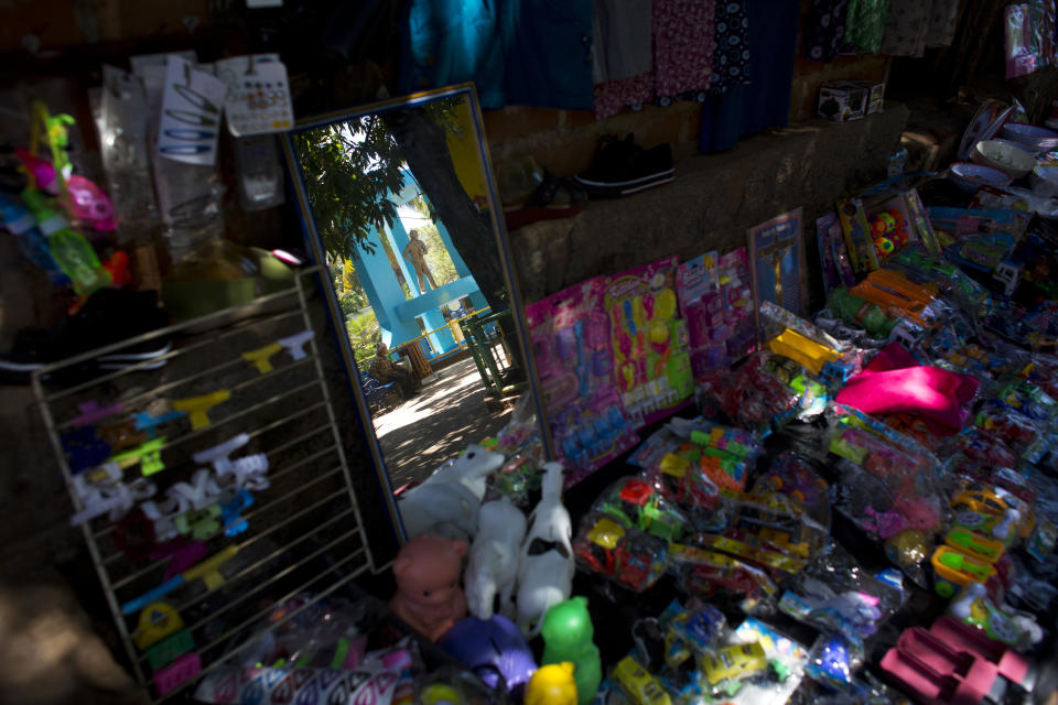 In this Aug. 18, 2018 photo, a statue of a young migrant traveling to the U.S. is reflected in a shop mirror, on the central square in Intipuca, El Salvador. The hero statue is in the town's main plaza, Parque Los Emigrantes, or Immigrants Park, and carries a backpack. (AP Photo/Rebecca Blackwell)