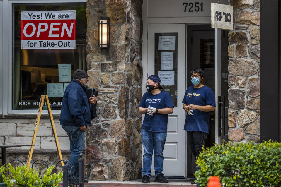 Fish Taco restaurant workers talk to a customer, left, in front of the restaurant in Bethesda, Md., Monday, May 11, 2020. As states push for some return to normal business operations, elected officials in the Virginia and Maryland suburbs surrounding Washington, D.C., are unwilling to quickly reopen, as they confront COVID-19 infection and fatality numbers that are the highest in their states. (AP Photo/Manuel Balce Ceneta)