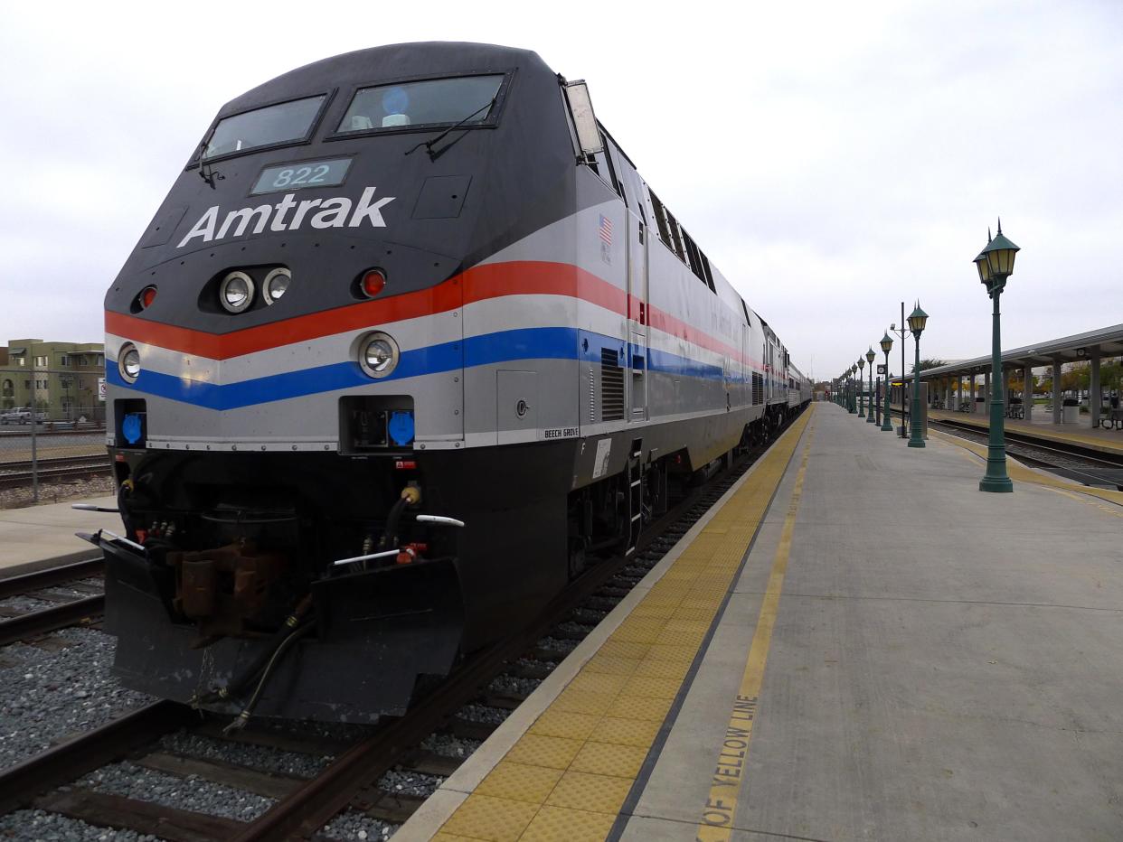 Gray, red, and blue amtrak train on track at station