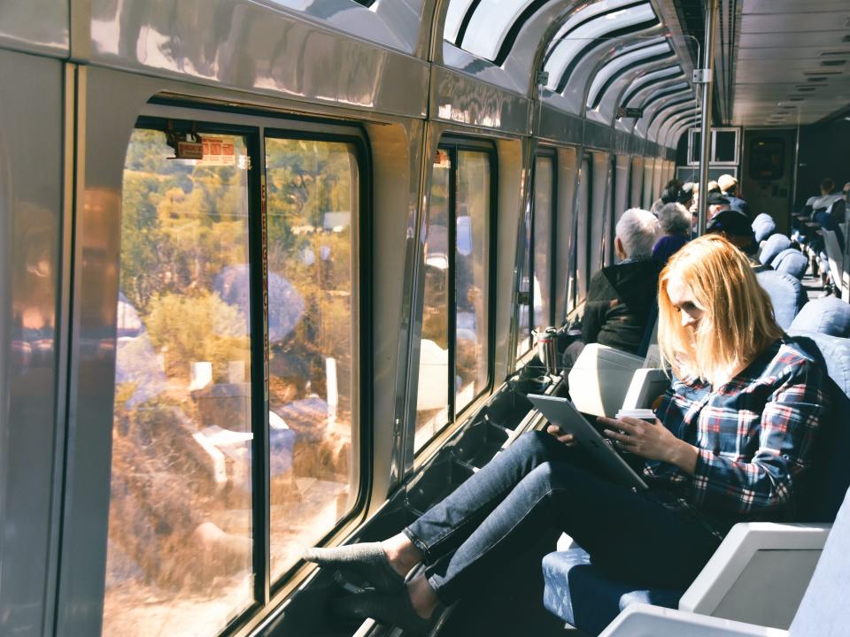 a woman reading a book in a seat on amtrak train in front of a window
