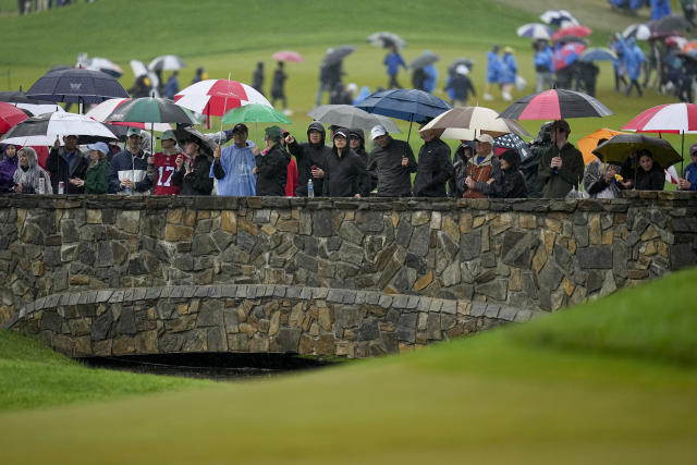 Fans watch in the rain on the first hole during the third round of the PGA Championship golf tournament at Oak Hill Country Club on Saturday, May 20, 2023, in Pittsford, N.Y. (AP Photo/Abbie Parr)