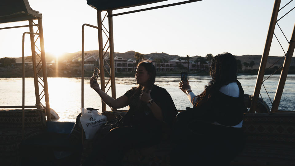 Two people on a boat on a river taking selfies at first light