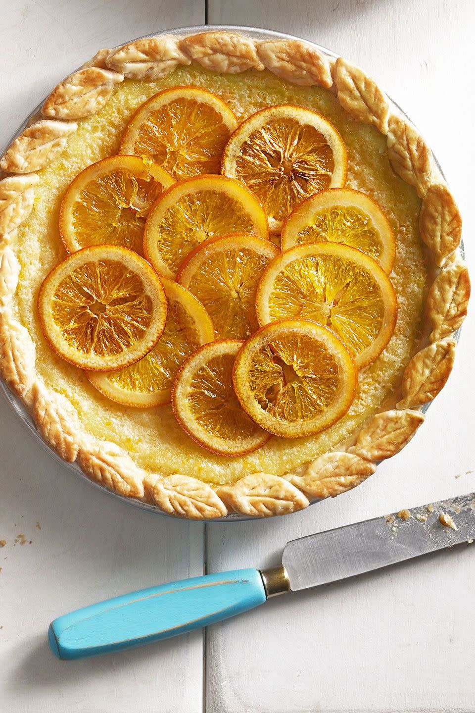 orange buttermilk chess pie with candied orange slices on top and pie crust leaves around the border