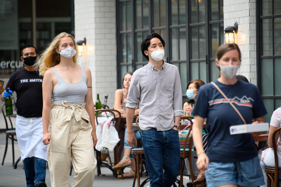 NEW YORK, NEW YORK - JUNE 30: People wear a protective face mask outside The Smith on the Upper East Side as New York City moves into Phase 2 of re-opening following restrictions imposed to curb the coronavirus pandemic on June 30, 2020. Phase 2 permits the reopening of offices, in-store retail, outdoor dining, barbers and beauty parlors and numerous other businesses. Phase 2 is the second of four phased stages designated by the state. (Photo by Noam Galai/Getty Images)