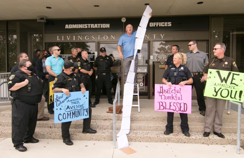 Members of the Livingston County Sheriff’s Department flank Genoa Township resident Kurt Skarjune, who holds a string of sheets of paper containing messages of support for law enforcement officers, in front of the Sheriff’s Department Wednesday, Sept. 2, 2020.