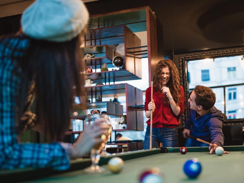 Group of friends spending time together, drinking beer, playing snooker - stock photo