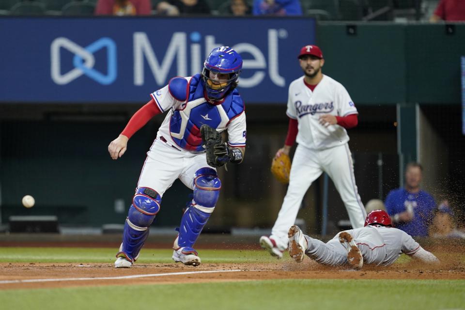 Texas Rangers catcher Jonah Heim waits on the throw as Los Angeles Angels' Luis Rengifo scores on a Mike Trout two-run double in the third inning of a baseball game in Arlington, Texas, Thursday, Sept. 22, 2022. Rangers starting pitcher Martin Perez, rear, looks on at the play that also scored Magneuris Sierra. (AP Photo/Tony Gutierrez)