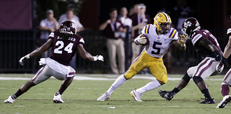 LSU running back Derrius Guice (5) tries to run away from Mississippi State defensive back Chris Rayford (24) and linebacker Dezmond Harris (11) during the first half of their NCAA college football game against in Starkville, Miss., Saturday, Sept. 16, 2017. (AP Photo/Rogelio V. Solis)