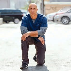 Dr. Kwane Stewart kneeling on one knee for a portrait.