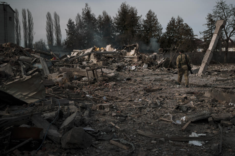 A volunteer of the Ukrainian Territorial Defense Forces walks on the debris of a car wash destroyed by a Russian bombing in Baryshivka, east of Kyiv, Ukraine, Friday, March 11, 2022. (AP Photo/Felipe Dana)