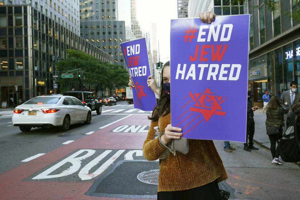 A young woman holds a sign toward oncoming traffic on Third Avenue outside the offices of New York Gov. Andrew Cuomo, Thursday, Oct. 15, 2020, in New York. Some members of the Jewish community are angered at Cuomo's recent move ordering schools to close in Orthodox Jewish communities in Brooklyn and north of New York City where coronavirus cases are trending upward. Three Rockland County Jewish congregations filed a lawsuit Wednesday accusing Cuomo of engaging in a streak of anti-Semitic discrimination with a crackdown on religious gatherings. (AP Photo/Kathy Willens)